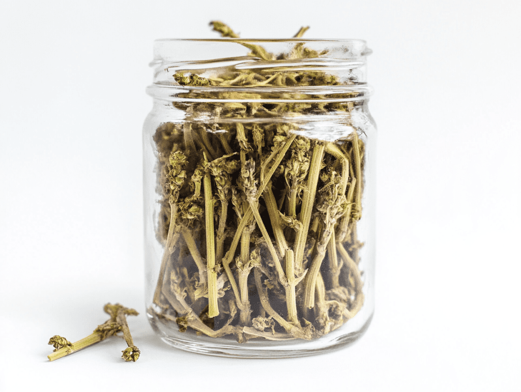 Cannabis stems arranged beside a cup of cannabis tea and infused oil, showing different ways to reuse leftover cannabis stems.